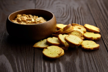 Bruschette chips , baked bread, roasted peanut peeled in a wooden bowl