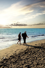 Naklejka premium senior couple walking on the beach at sunset