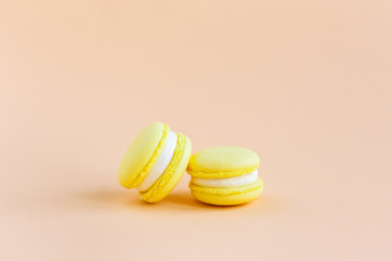 Yellow macarons on a peach pastel background.