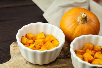 Baked pumpkin in white ceramic bowl on wooden background