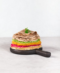 Colored pancakes with beets, cocoa, carrots and spinach on a light background