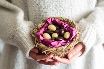 Fototapeta na wymiar Woman hands holding a nest with sweet Easter almonds
