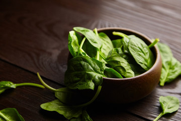 Spinach fresh green leaves in a wooden bowl on brown table