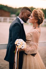 An African man and a Caucasian woman romantically touch each other in the sunset light. Close-up...