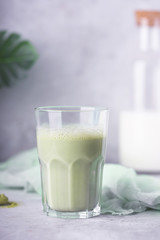 Green matcha latte with almond milk on a gray