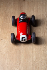 Fototapeta premium Red toy vintage retro racing car detail on a hardwood surface