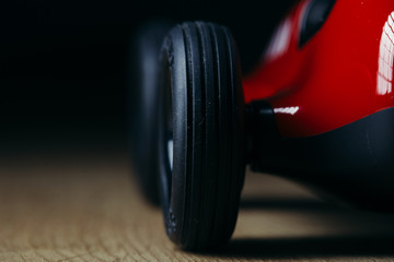 Obraz na płótnie Canvas Red toy vintage retro racing car detail on a hardwood surface black tyre wheel