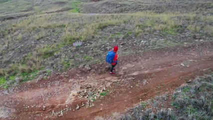 Young female backpacker hiking by footpath on Sao Lourenco headland with Atlantic ocean bay view in the end of February, Madeira island, Portugal. Active people around  World traveling concept image.