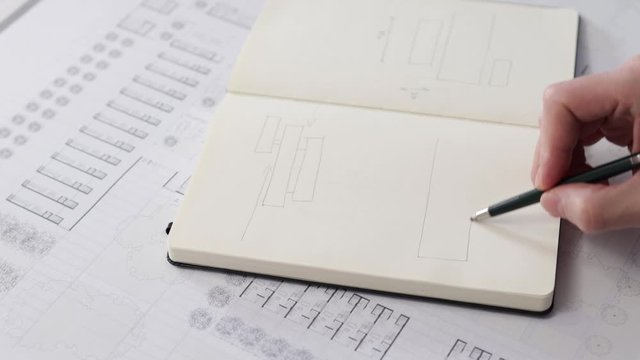 Architect's hands drawing a sketch in his notebook