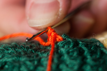 Woman knits crochet. The girl sits on the couch and knits from knitting yarn