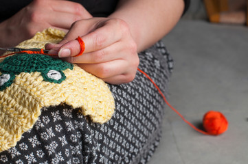 Woman knits crochet. The girl sits on the couch and knits from knitting yarn