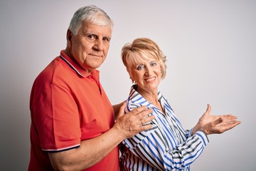 Senior beautiful couple standing together over isolated white background pointing aside with hands open palms showing copy space, presenting advertisement smiling excited happy