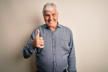 Senior handsome hoary man wearing casual shirt standing over isolated white background doing happy thumbs up gesture with hand. Approving expression looking at the camera showing success.