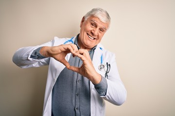 Senior handsome hoary doctor man wearing coat and stethoscope over white background smiling in love doing heart symbol shape with hands. Romantic concept.