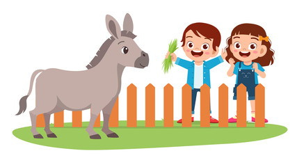 Obraz na płótnie Canvas happy cute little kid boy and girl feed donkey