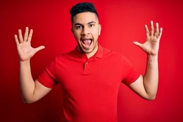 Fototapeta premium Young handsome man wearing red casual polo standing over isolated background celebrating crazy and amazed for success with arms raised and open eyes screaming excited. Winner concept
