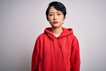 Fototapeta premium Young beautiful asian girl wearing casual sweatshirt with hoodie over white background skeptic and nervous, frowning upset because of problem. Negative person.