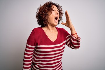 Middle age beautiful curly hair woman wearing casual striped sweater over white background shouting and screaming loud to side with hand on mouth. Communication concept.