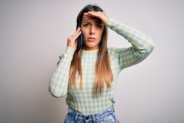 Young blonde woman having a conversation talking on smartphone over isolated background stressed with hand on head, shocked with shame and surprise face, angry and frustrated. Fear and upset