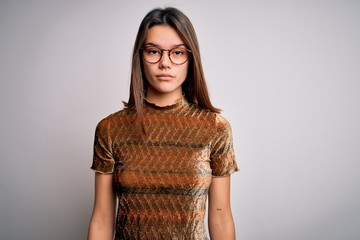 Young beautiful brunette girl wearing casual t-shirt and glasses over isolated white background with serious expression on face. Simple and natural looking at the camera.