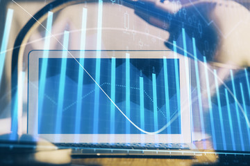 Naklejka premium Stock market chart hologram drawn on personal computer background. Double exposure. Concept of investment.