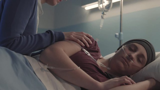 Caring woman assisting her friend with cancer at the hospital