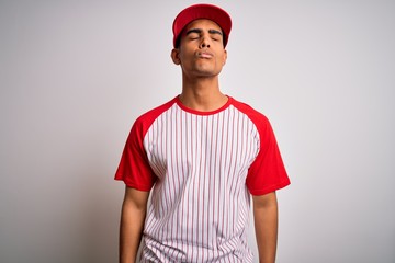 Young handsome african american sportsman wearing striped baseball t-shirt and cap looking at the camera blowing a kiss on air being lovely and sexy. Love expression.