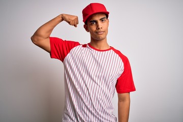 Young handsome african american sportsman wearing striped baseball t-shirt and cap Strong person showing arm muscle, confident and proud of power