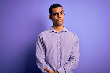 Handsome african american man wearing striped shirt and glasses over purple background skeptic and nervous, frowning upset because of problem. Negative person.