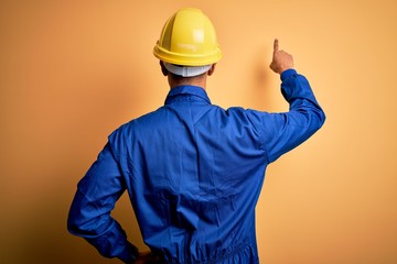 Young handsome african american worker man wearing blue uniform and security helmet Posing...