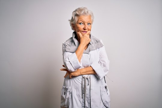 Senior beautiful grey-haired woman wearing casual jacket standing over white background with hand on chin thinking about question, pensive expression. Smiling with thoughtful face. Doubt concept.