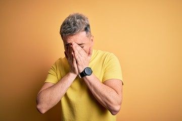 Young handsome modern man wearing yellow shirt over yellow isolated background with sad expression covering face with hands while crying. Depression concept.