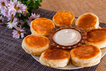 Cheesecakes on a plate on a brown background. Dish of cottage cheese for breakfast.