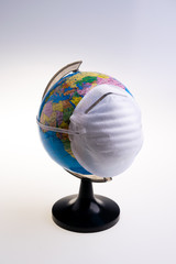 Protective surgical face mask on a terrestrial globe model. Coronavirus Concept. Surgical mask with rubber ear straps. Corona virus,  nCoV, covid 19.  Coronavirus outbreak.