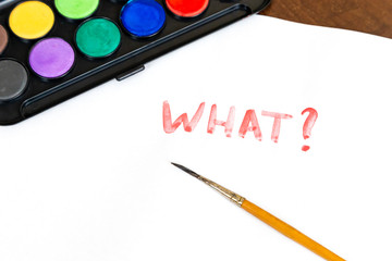 Handwritten what text with brush and watercolor paints on white background. Box of watercolor...