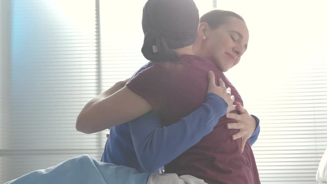 Caring woman hugging her friend with cancer at the hospital