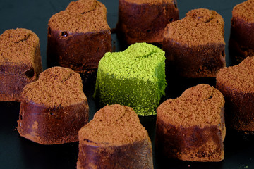 Heart shaped Japanese Nama chocolate, a type of ganache, made from a mix of melted cacao and fresh cream and sprinkled with Cocao powder and Mutcha green tea powder on top. Selective focus