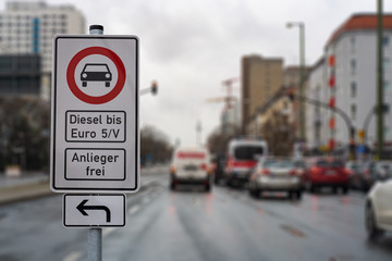 german street sign diesel driving ban in the downtown with a blurred background of city traffic, cars, traffic lights and buildings