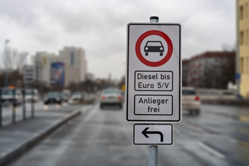 german street sign diesel driving ban in the downtown with a blurred background of city traffic, cars, traffic lights and buildings