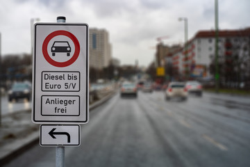 german street sign diesel driving ban in the downtown with a blurred background of city traffic, cars, traffic lights and buildings