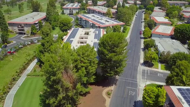 Aerial pull back view above retirement condominium complex rooftop solar panels generating solar electricity