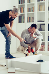 Fototapeta premium Mature man assembling furniture with his brother.