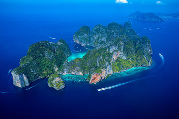 Top view of isolated rocky tropical island with turquoise water and white beach.