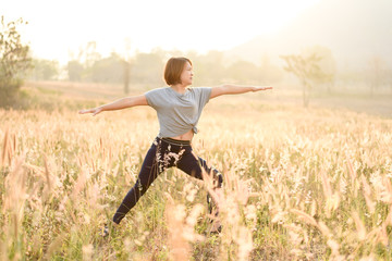Fototapeta premium Young woman do yoga on a field