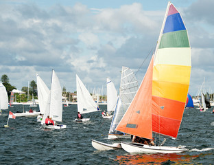 Racing Cat sailboat closeup with a bright multicoloured sail competing in a junior sailing regatta....