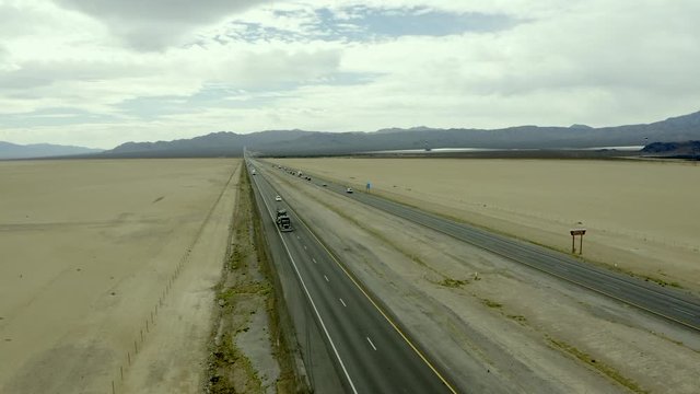 Trucks and vehicles driving along Interstate Fifteen in Mojave Desert, aerial