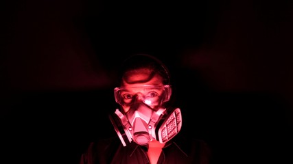 Woman in the heavy duty biohazard medical mask in the darkness and red light. Personal forced home...