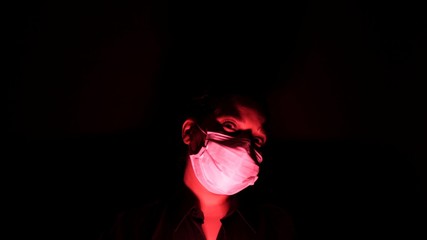 Woman in the surgical medical mask in the darkness and red light. Personal forced home quarantine...