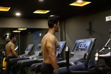 Fototapeta na wymiar An young and handsome Indian Bengali brunette man with muscular body doing exercise in a multi gym. Fitness and Indian lifestyle.