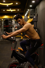 Fototapeta na wymiar An young and handsome Indian Bengali brunette man with muscular body doing cycling in a multi gym. Fitness and Indian lifestyle.